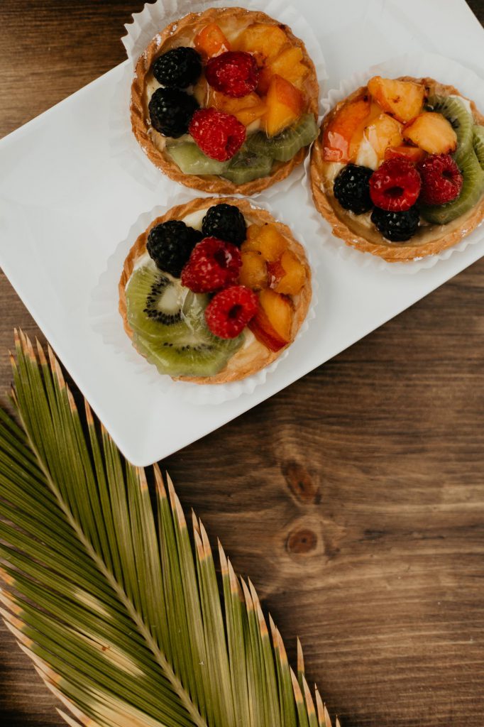 mini fruit tarts next to a palm leaf
