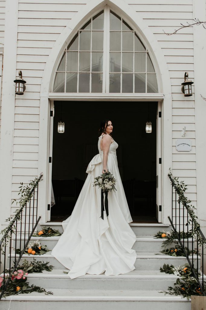 bride posing in front of the church doors