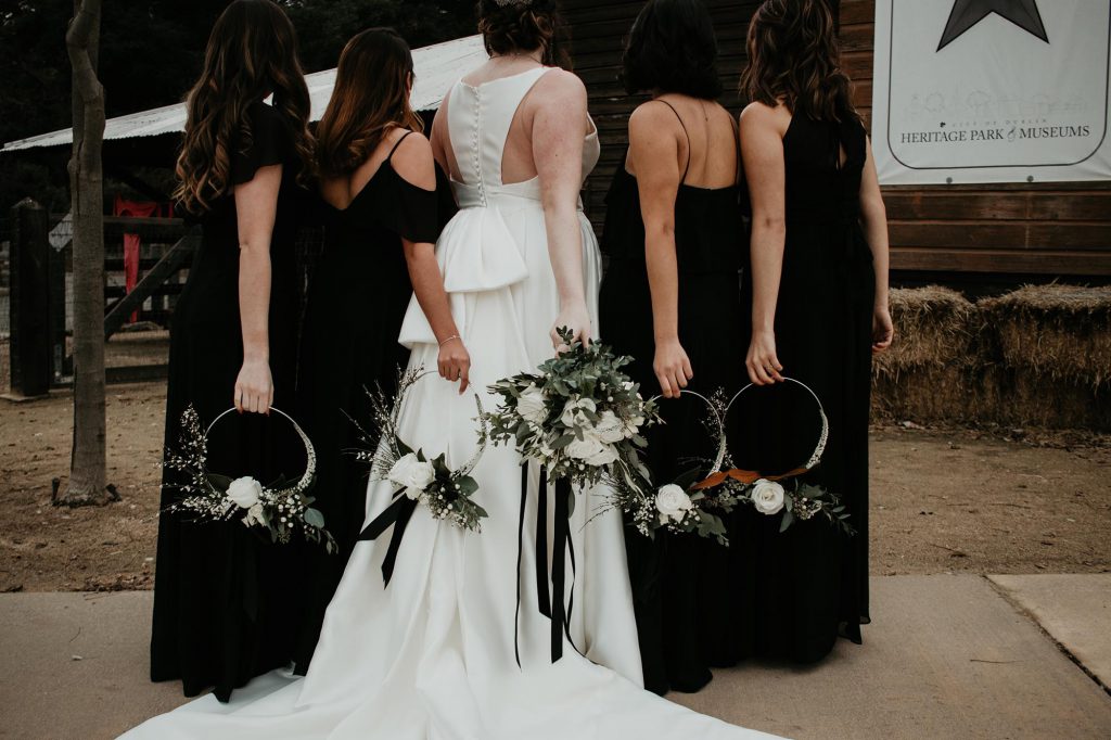 bride and bridesmaids holding floral rings behind them