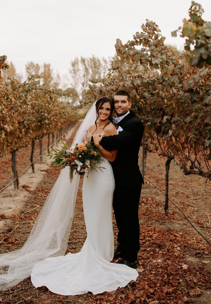 bride and groom with bouquet in a vineyard
